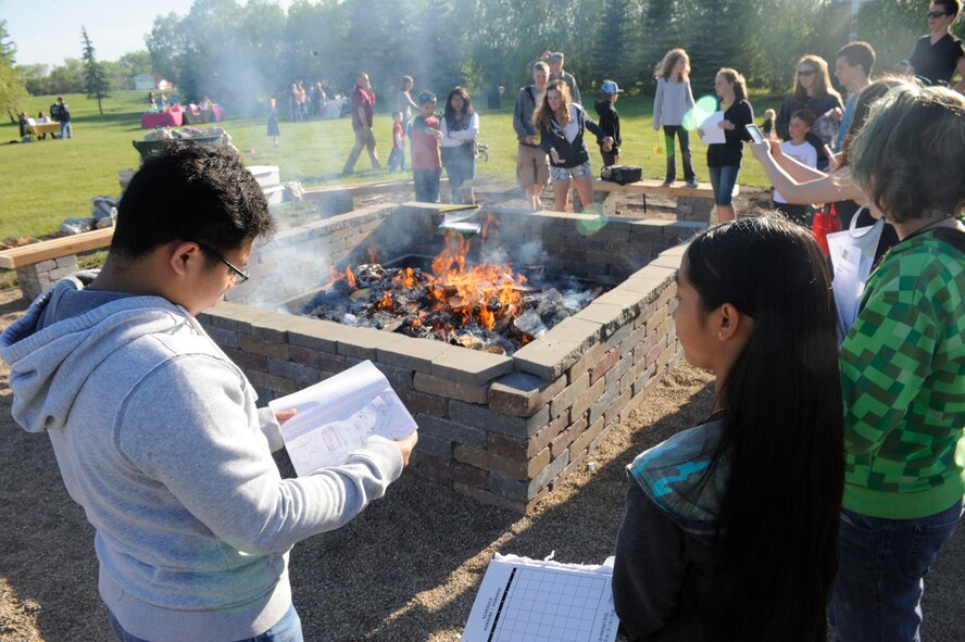 Base children toss their old school notebooks into a bonfire during the Balfour Beatty notebook burn at Minot Air Force Base, N.D., June 3, 2015. The burn featured a variety of family friendly attractions and served as a way for children to celebrate the start of summer vacation. (U.S. Air Force photo/Senior Airman Stephanie Morris)