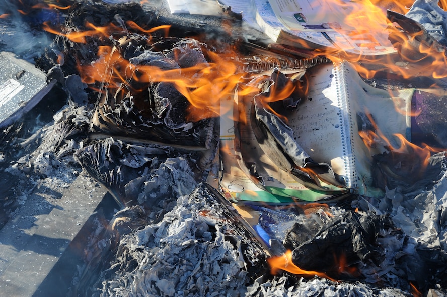 Flames lap at the curled edges of a composition book during the Balfour Beatty notebook burn at Minot Air Force Base, N.D., June 3, 2015. The burn featured a variety of family friendly attractions and served as a way for children to celebrate the start of summer vacation. (U.S. Air Force photo/Senior Airman Stephanie Morris)
