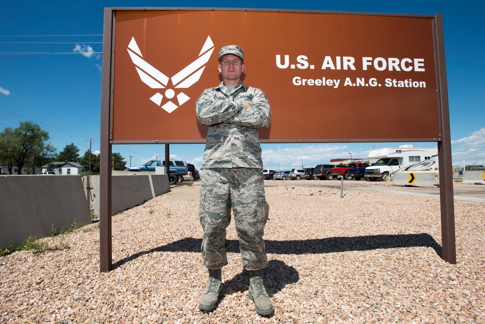U.S. Air Force Senior Airman Jonathan R. Smail, a transmission technician from the 233rd Space Communications Squadron, Colorado Air National Guard, poses in front of the Greeley Air National Guard Station sign, Greeley, Colo., June 7, 2015. Smail, who troubleshoots and maintains satellite communications electronic equipment for the 233rd's one-of-a-kind mobile nuclear and missile launch tracking mission, won the 2014 Air National Guardsman of the year. (Air National Guard photo by Tech. Sgt. Wolfram M. Stumpf)