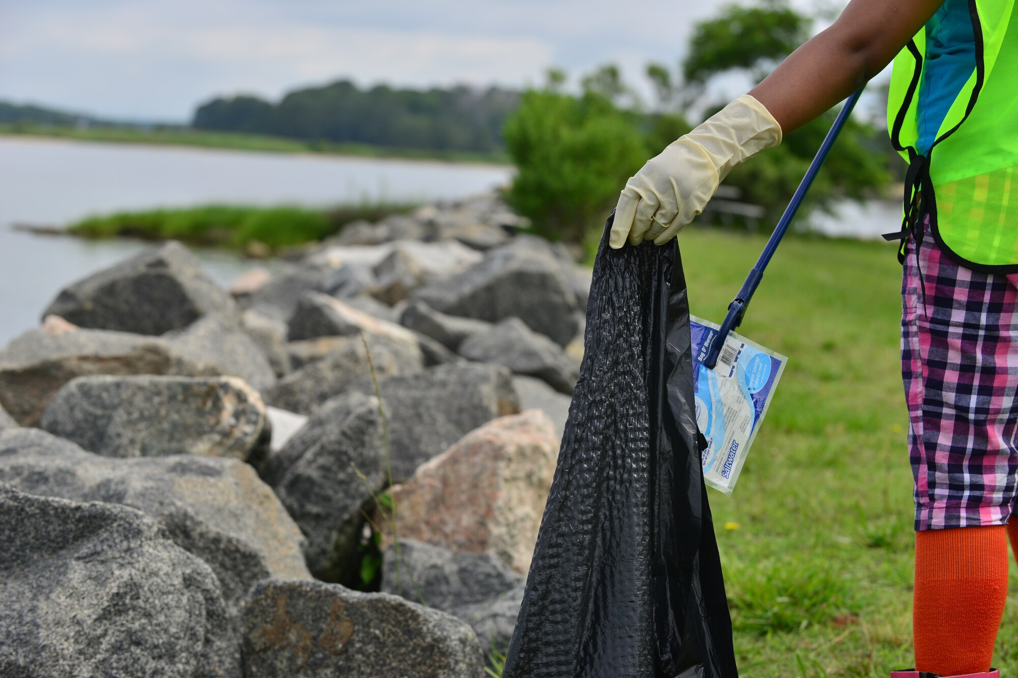Jourdan Griffin, daughter of U.S. Army Capt. Wayne Griffin, Bravo Company, 1st Battalion, 210th Aviation Regiment commander collects trash along the Fort Eustis, Va., shoreline June 6, 2015. The shoreline borders the Chesapeake Bay, the county’s largest estuary with 1,500 square miles of wetlands. (U.S. Air Force photo by Staff Sgt. Natasha Stannard/Released)