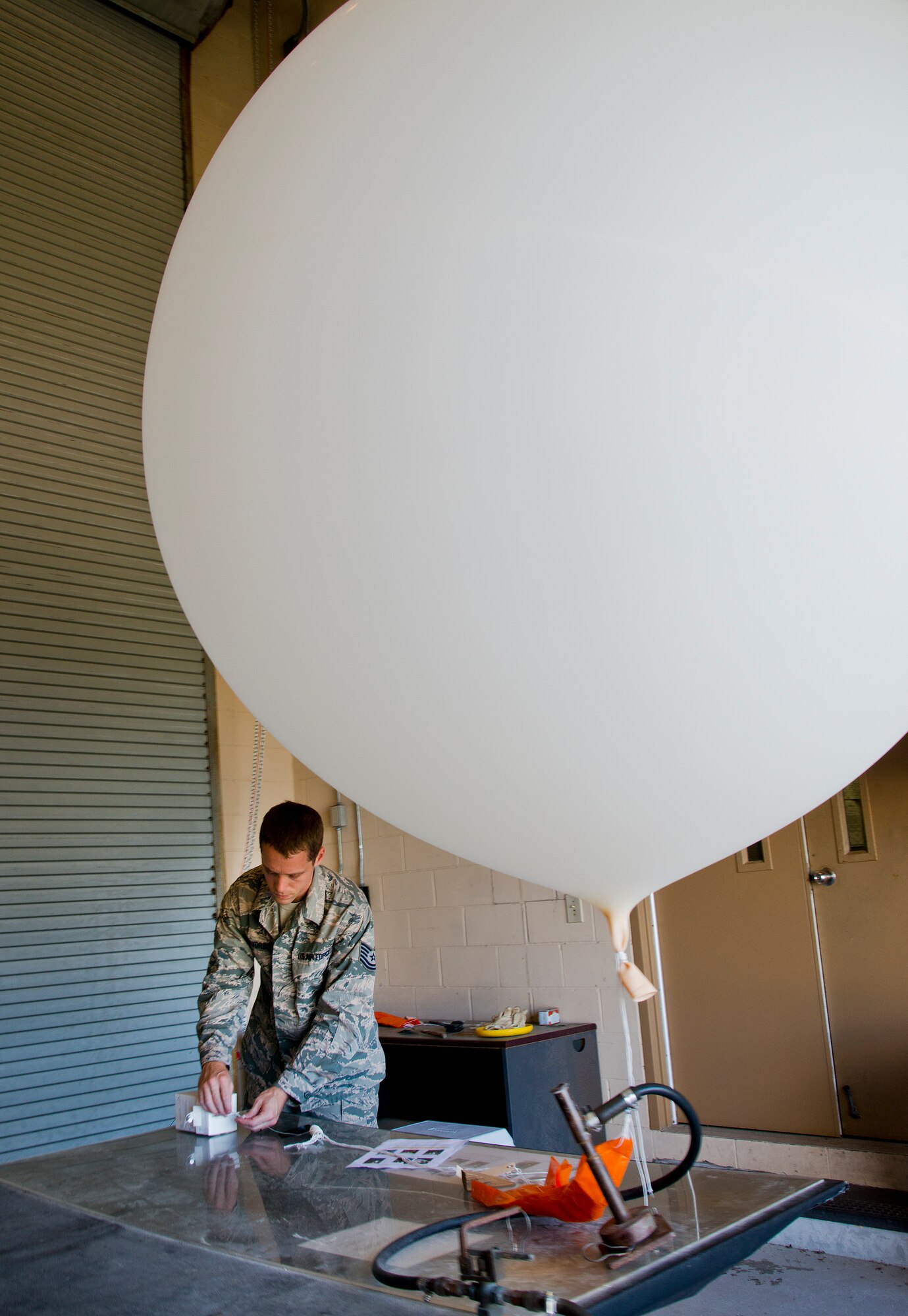 Tech. Sgt. Nathan Halvorson, 96th Weather Flight, secures a SONDE box to the end of an orange parachute on a weather balloon prior to a launch from Eglin Air Force Base, Fla.  The box collects data such as the GPS coordinates, wind speed, direction, height, ascension rate, pressure, temperature and humidity.  This information is collected by the 96th Weather Flight and provided to test engineers.  The engineers used the data in aircraft test evaluations.  (U.S. Air Force photo/Samuel King Jr.) 