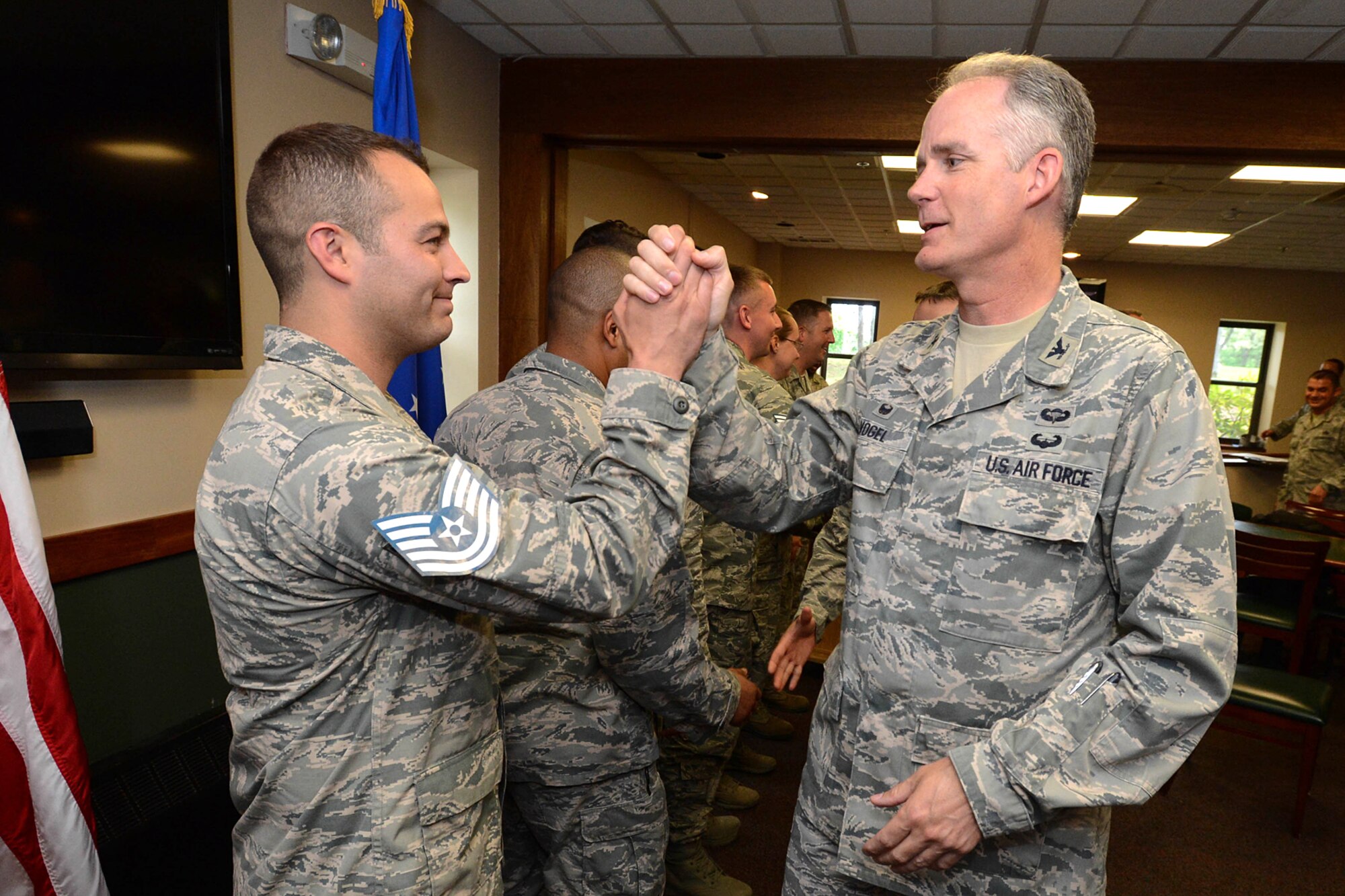 Col. Michael A. Vogel, 66th Air Base Group and installation commander, high-fives Staff Sgt. Matthew R. Marquart, 66th Security Forces Squadron Combat Arms NCO in charge, on being selected for promotion to technical sergeant during a recognition ceremony at the Minuteman Commons June 9. Marquart and 12 other Airmen assigned to Hanscom were selected for promotion to technical sergeant. (U.S. Air Force photo by Jerry Saslav)