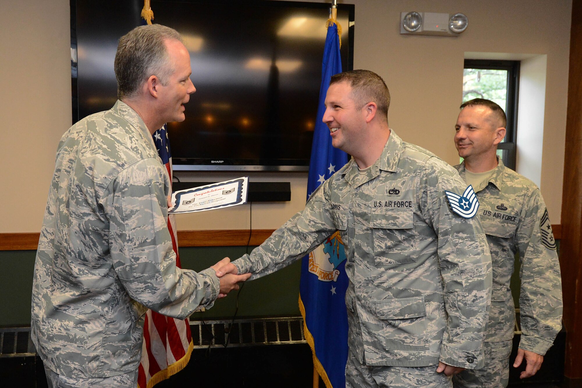 Col. Michael A. Vogel, 66th Air Base Group and installation commander, congratulates Staff Sgt. Samuel D. Harris, 319th Recruiting Squadron trainer, on being selected for promotion to technical sergeant during a recognition ceremony at the Minuteman Commons June 9. Harris and 12 other Airmen assigned to Hanscom were selected for promotion to technical sergeant. (U.S. Air Force photo by Jerry Saslav)
