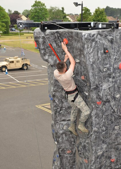 U.S. Air Force Airman 1st Class Anthony Tidwell, 100th Force Support Squadron force management apprentice from St. Paul, Minn., hits the buzzer as he reaches the top of the wall climb at the Unaccompanied Airmen’s Appreciation Day event June 5, 2015, on RAF Mildenhall, England. Single Airmen of all ranks participated in a variety of activities including an inflatable boxing ring, dunk tank and Chiefs vs. Eagles vs. Airmen Defender Challenge course. (U.S. Air Force photo by Karen Abeyasekere/Released)