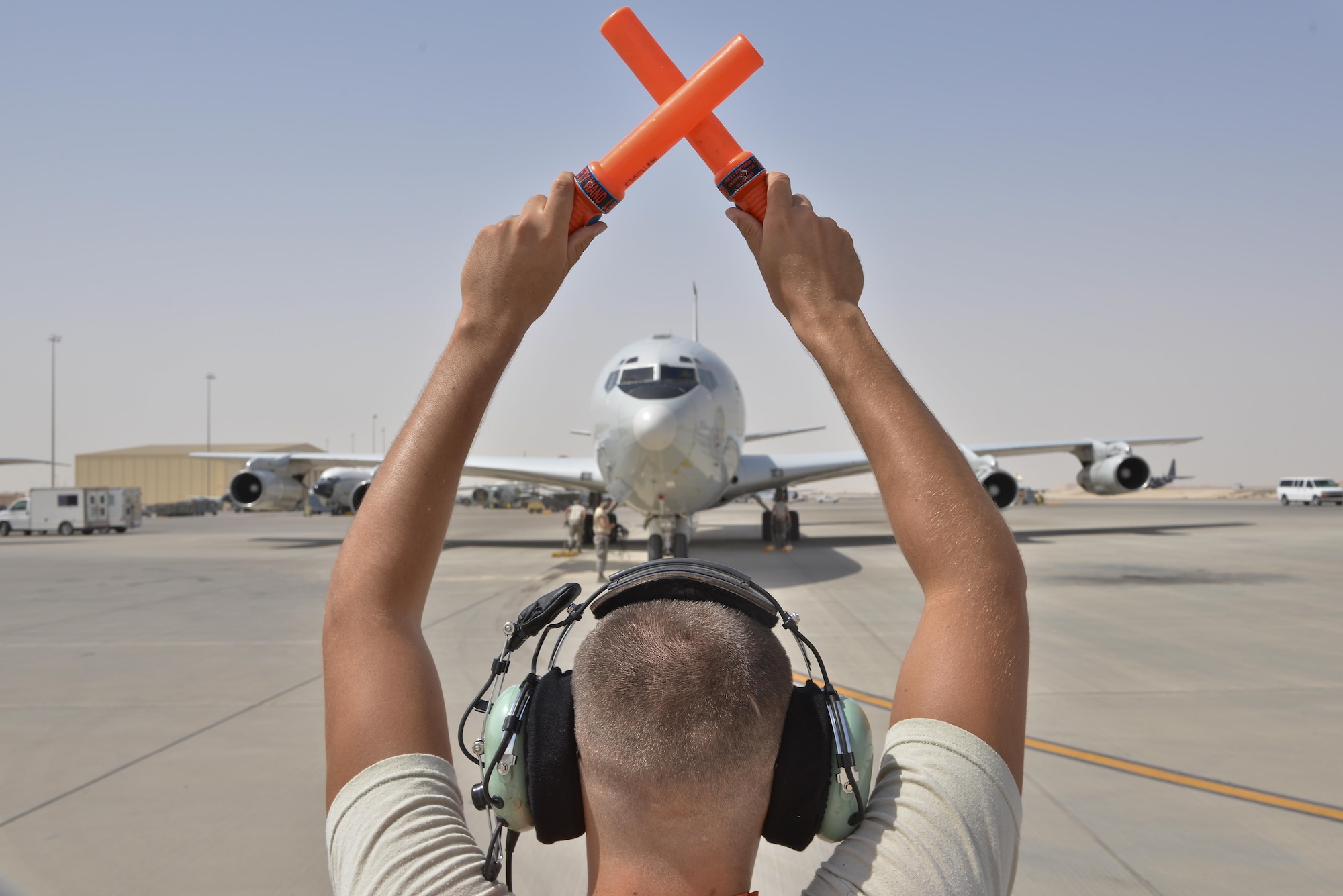 An Airman form the 7th Expeditionary Air Mobility Unit directs a Boeing E-8C Joint Surveillance Target Attack Radar Systems aircraft to park after completing its 100K combat hours milestone mission June 2, 2015 Al Udeid Air Base, Qatar. The E-8C JSTARS and its active duty, guard and reserve service members conduct missions overseas to support operations on the war on terror. During this time JSTARS completed 100K combat hours by continually flying 24/7 for 11.4 years. (U.S. Air Force photo/Staff Sgt. Alexandre Montes)