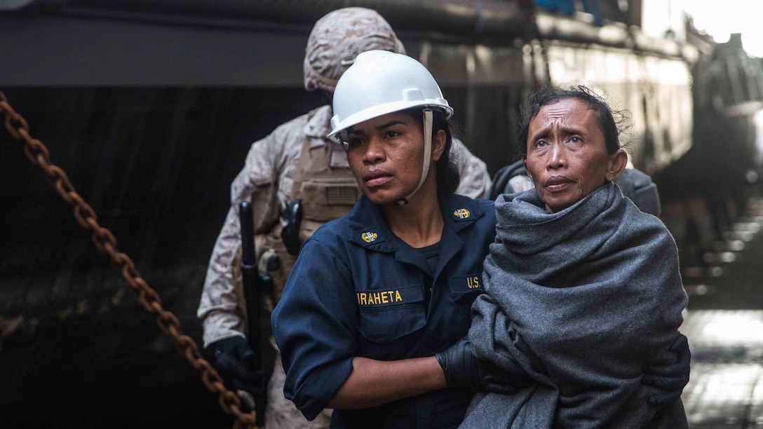 A U.S Navy Sailor assists a distressed mariner to medical staff aboard the USS Rushmore (LSD 47) at sea in the Makassar Strait, June 10, 2015. Rushmore rendered assistance to the distressed mariners in the waters between the Indonesian islands of Kalimantan and Sulawesi. Once on board, evacuees were provided food and medical attention by Marines and sailors of the 15th Marine Expeditionary Unit and Essex Amphibious Ready Group. 