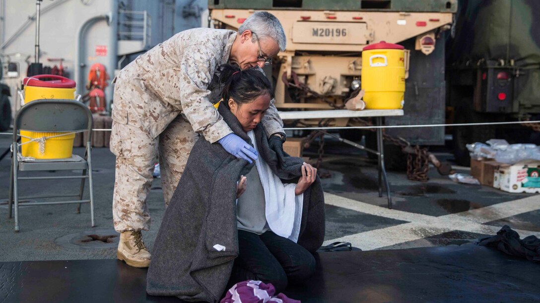 U.S. Navy Lt. Diane Hampton, the chaplain for Combat Logistics Battalion 15, 15th Marine Expeditionary Unit, comforts an evacuee aboard the USS Rushmore (LSD 47), after she was rescued from a sinking craft in the waters between the Indonesian islands of Kalimantan and Sulawesi, June 10, 2015. Once on board, evacuees were provided food and medical attention by Marines and sailors of the 15th Marine Expeditionary Unit and Essex Amphibious Ready Group. 