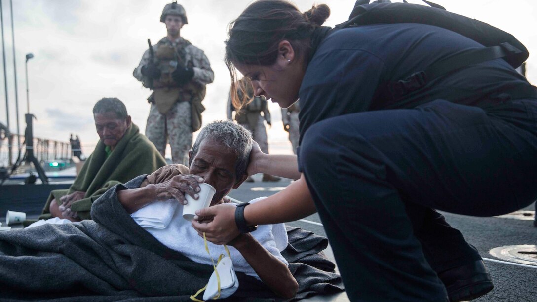 A U.S. Navy Sailor provides water to a distressed mariner aboard the USS Rushmore (LSD 47) at sea in the Makassar Strait, June 10, 2015. Rushmore rendered assistance to the distressed mariners in the waters between the Indonesian islands of Kalimantan and Sulawesi. Once on board, evacuees were provided food and medical attention by Marines and sailors of the 15th Marine Expeditionary Unit and Essex Amphibious Ready Group. 