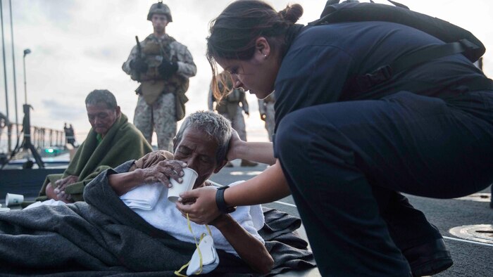 A U.S. Navy Sailor provides water to a distressed mariner aboard the USS Rushmore (LSD 47) at sea in the Makassar Strait, June 10, 2015. Rushmore rendered assistance to the distressed mariners in the waters between the Indonesian islands of Kalimantan and Sulawesi. Once on board, evacuees were provided food and medical attention by Marines and sailors of the 15th Marine Expeditionary Unit and Essex Amphibious Ready Group. 