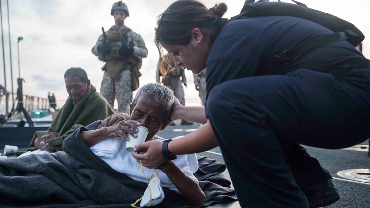 A U.S. Navy Sailor provides water to a distressed mariner aboard the USS Rushmore (LSD 47) at sea in the Makassar Strait, June 10, 2015. Rushmore rendered assistance to the distressed mariners in the waters between the Indonesian islands of Kalimantan and Sulawesi. Once on board, evacuees were provided food and medical attention by Marines and sailors of the 15th Marine Expeditionary Unit and Essex Amphibious Ready Group. 