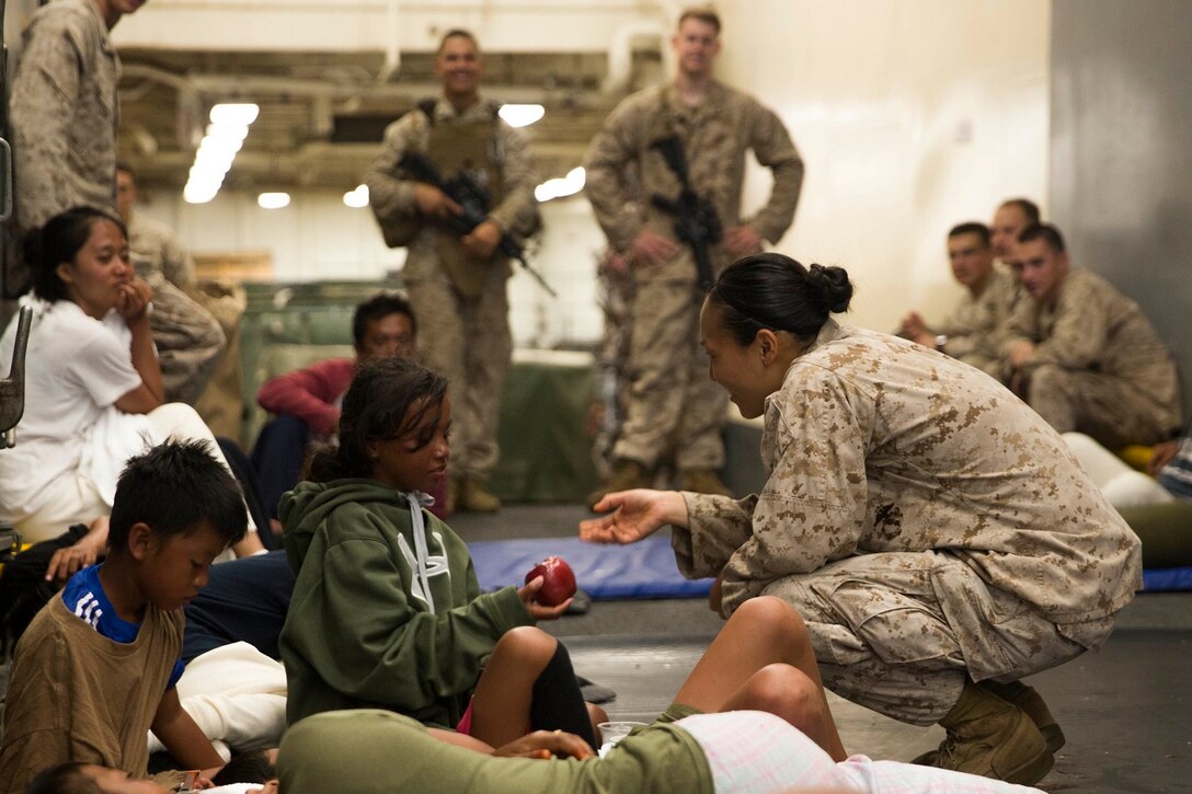U.S. Marine Cpl. Jennifer Ko gives an apple to a distressed mariner aboard the USS Rushmore (LSD 47), after she was rescued from a sinking craft in the Makassar Strait, June 11, 2015. Ko is a supply warehouse clerk with Combat Logistics Battalion 15, 15th Marine Expeditionary Unit. Once on board, distressed mariners were provided food and medical attention by Marines and Sailors of the 15th MEU and Essex Amphibious Ready Group before being transferred to an Indonesian coast guard vessel. (U.S. Marine Corps photo by Sgt. Emmanuel Ramos/Released)