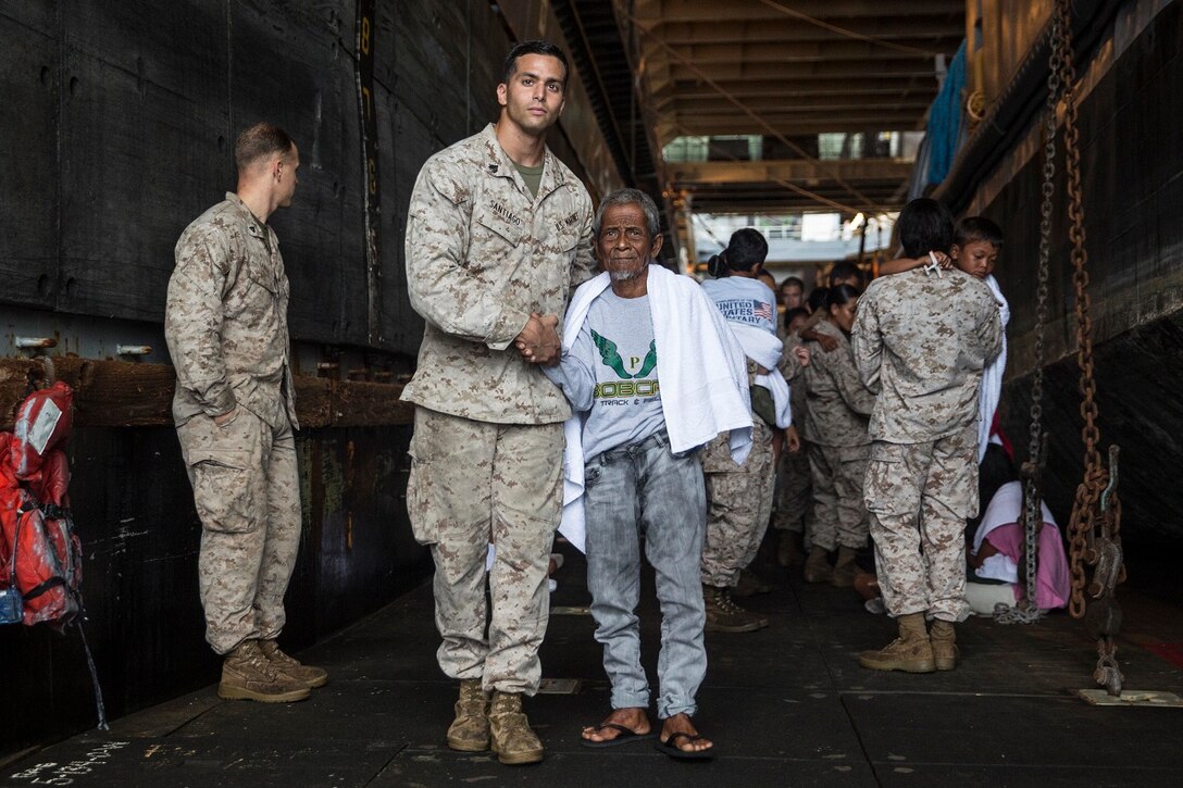 U.S. Marines with the 15th Marine Expeditionary Unit assist distressed mariners ready to be transported to an Indonesian coast guard vessel from the USS Rushmore (LSD 47), June 11, 2015. The distressed mariners were rescued from a sinking craft in Makassar Strait. Once on board USS Rushmore, the mariners were provided food and medical attention by Marines and Sailors of the 15th MEU and Essex Amphibious Ready Group before being transferred to the coast guard vessel. (U.S. Marine Corps photo by Sgt. Emmanuel Ramos/Released)