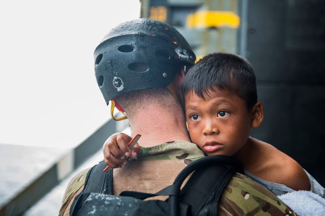 A U.S. Sailor with the Essex Amphibious Ready Group loads an Indonesia boy onto a watercraft to be transported to an Indonesian coast guard vessel from the USS Rushmore (LSD 47) in the Pacific Ocean, June 11, 2015. Rushmore rendered assistance to the distressed mariners in the waters between the Indonesian islands of Kalimantan and Sulawesi. Once on board, the mariners were provided food and medical attention by Marines and Sailors of the 15th Marine Expeditionary Unit and Essex Amphibious Ready Group. (U.S. Marine Corps photo by Sgt. Emmanuel Ramos/Released)