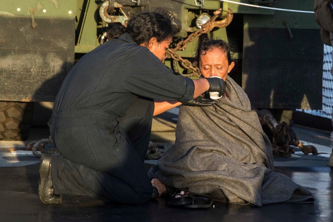A U.S. Navy Sailor provides water to a distressed mariner aboard the USS Rushmore (LSD 47) at sea in the Makassar Strait, June 10, 2015. Rushmore rendered assistance to the distressed mariners in the waters between the Indonesian islands of Kalimantan and Sulawesi. Once on board, evacuees were provided food and medical attention by Marines and sailors of the 15th Marine Expeditionary Unit and Essex Amphibious Ready Group. (U.S. Marine Corps photo by Sgt. Emmanuel Ramos/Released)