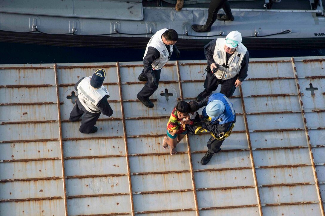 U.S. Marines and Sailors with the 15th Marine Expeditionary Unit and the Essex Amphibious Ready Group help distressed mariners board the USS Rushmore (LSD 47) in the Makassar Strait, June 10, 2015. Rushmore rendered assistance to the distressed mariners in the waters between the Indonesian islands of Kalimantan and Sulawesi. Once on board, evacuees were provided food and medical attention by Marines and sailors of the 15th Marine Expeditionary Unit and Essex Amphibious Ready Group. (U.S. Marine Corps photo by Sgt. Emmanuel Ramos/Released)