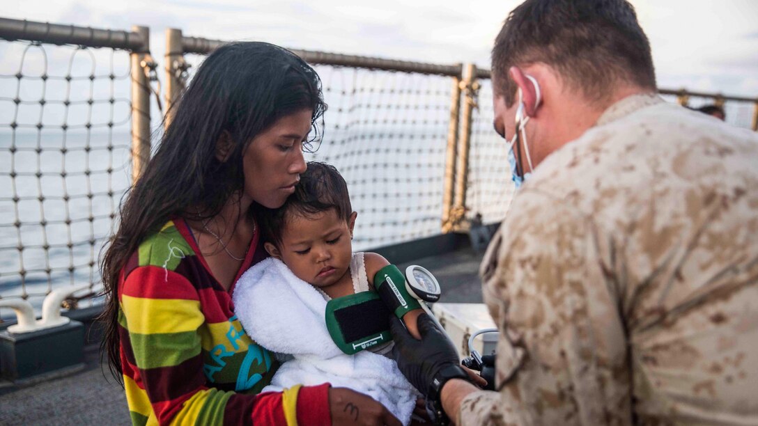 A U.S. Navy corpsman assigned to the 15th Marine Expeditionary Unit provides medical attention to a distressed mariner aboard the USS Rushmore (LSD 47) at sea in the Makassar Strait, June 10, 2015. Rushmore rendered assistance to the distressed mariners in the waters between the Indonesian islands of Kalimantan and Sulawesi. Once on board, evacuees were provided food and medical attention by Marines and sailors of the 15th Marine Expeditionary Unit and Essex Amphibious Ready Group. 