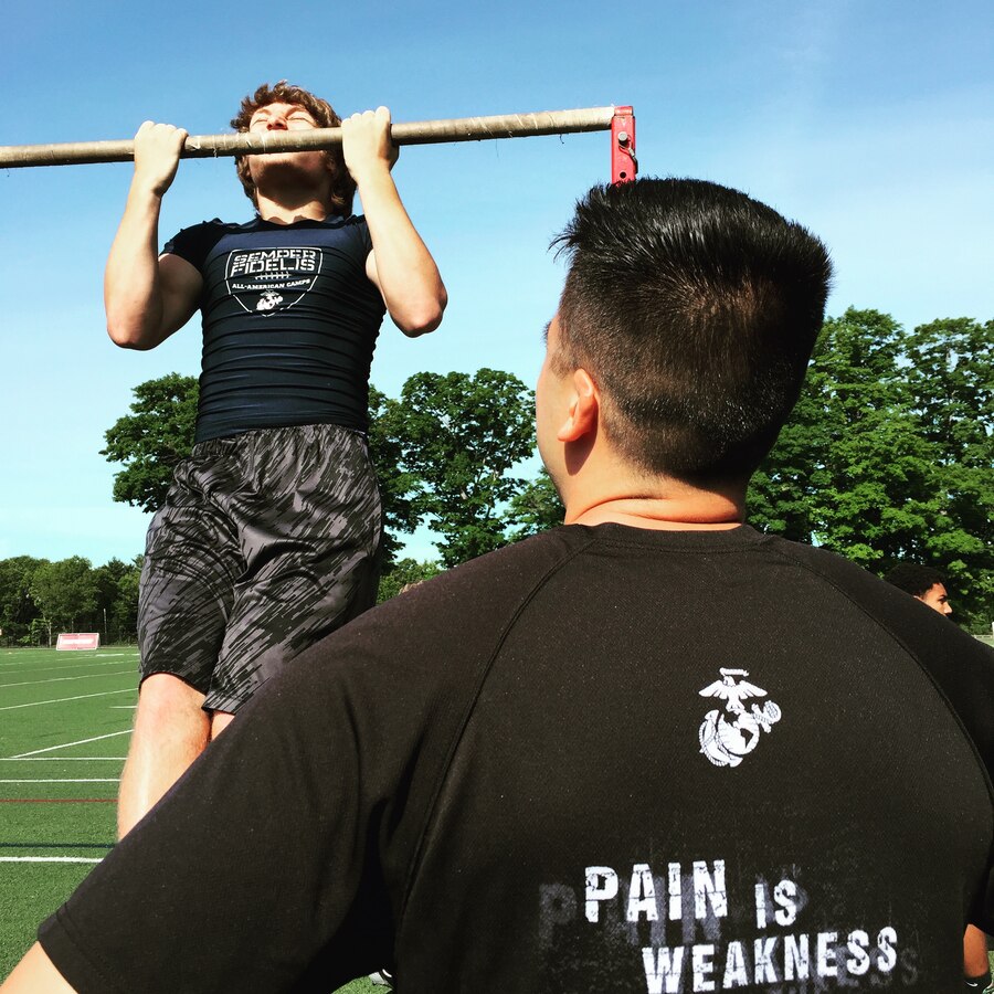 Staff Sgt. David Castro counts the pull-ups of Eric Duhamel, a running back for the East Bridgewater High School freshman football team of East Bridgewater, Mass., during the beginning hours of the Semper Fidelis All-American Camp at St. John Preparatory High School in Danvers, Massachusetts, June 7. Nearly 200 top football players from high schools throughout the New England states, including New York, Pennsylvania and New Jersey, received training from the NFL and college football coaches while fighting for a spot to play in the 2016 Semper Fidelis All-American Bowl game in California. Castro is a canvassing recruiter with Recruiting Substation Boston, Mass., Recruiting Station Portsmouth, New Hampshire.