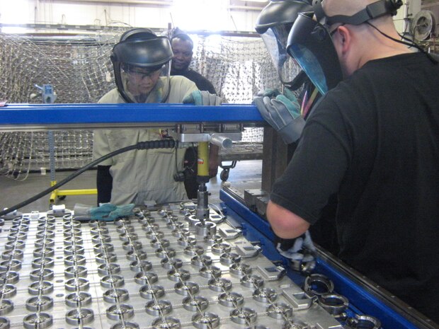 Southwest Regional Maintenance Center employees train Japan Regional Maintenance Center employees on a SWRMC designed and manufactured flight deck net making machine Nov. 13, 2014.