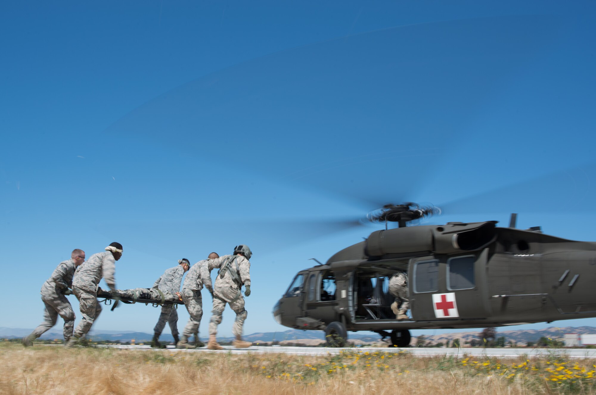 Medical technicians from the 349th Medical Group carry a litter with a simulated earthquake victim to a UH-60 Black Hawk helicopter June 6, 2015, at Travis Air Force Base, California, during an exercise. (U.S. Air Force photo by Ken Wright/Released)