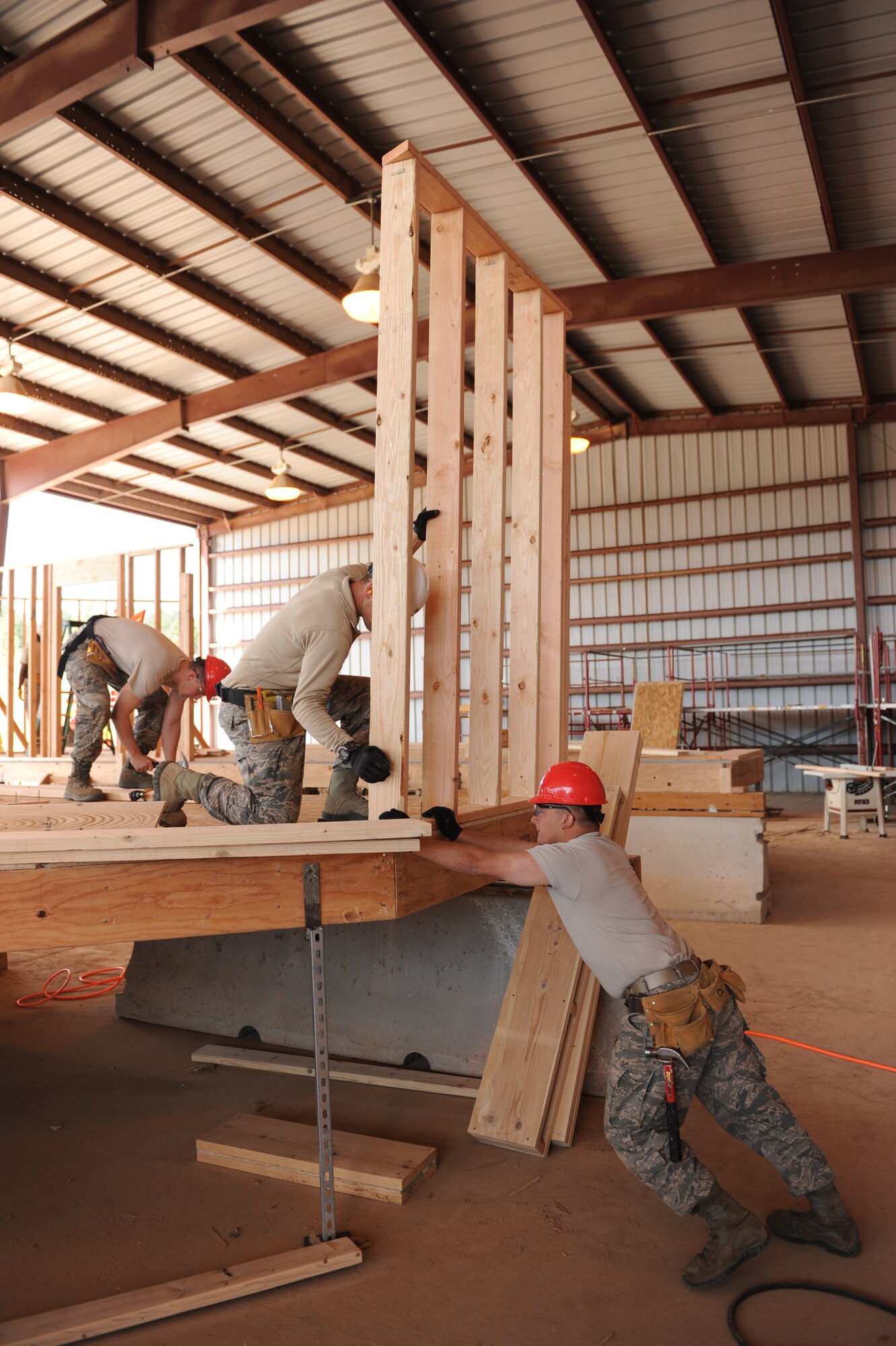 A cadet secures a wall frame while a civil engineering mentor prepares to secure the frame to the floor, May 31, 2015. U.S. Air Force Academy cadets are taking part in the Field Engineering and Readiness Laboratory by building two homes for the Navajo Nation in New Mexico and Arizona. (U.S. Air Force photo/John Van Winkle)

