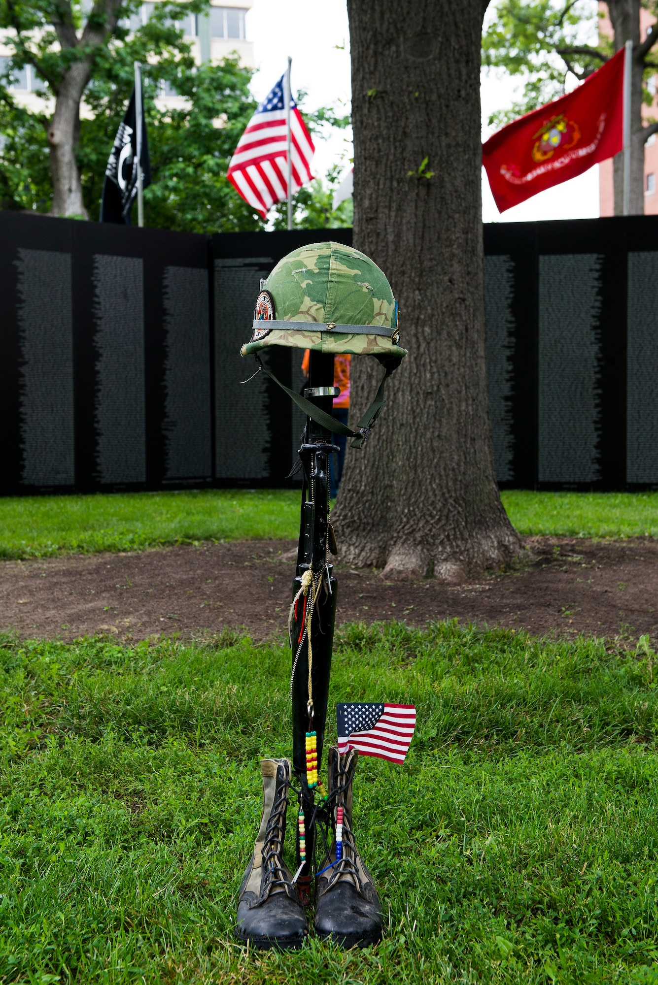 A battlefield cross, which is a compilation of a helmet, rifle and boots, is displayed in front of the Traveling Vietnam Wall at the Eternal Flame Park, St. Louis, Missouri, June 4, 2015. The battlefield cross is displayed to show honor and respect for the fallen troops. (U.S. Air Force Photo by Airman 1st Class Megan Friedl)