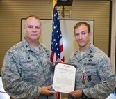 U.S. Air Force Capt. Robert Chance, 822d Base Defense Squadron operations officer, receives a Meritorious Service Medal certificate from Col. Michael Ross, 820th Base Defense Group commander, during an awards ceremony June 10, 2015, at Moody Air Force Base, Ga. Chance earned the award for his role in leading Airmen in the force protection of aircraft and personnel in Southwest Asia. (U.S. Air Force photo by Airman Greg Nash/Released)