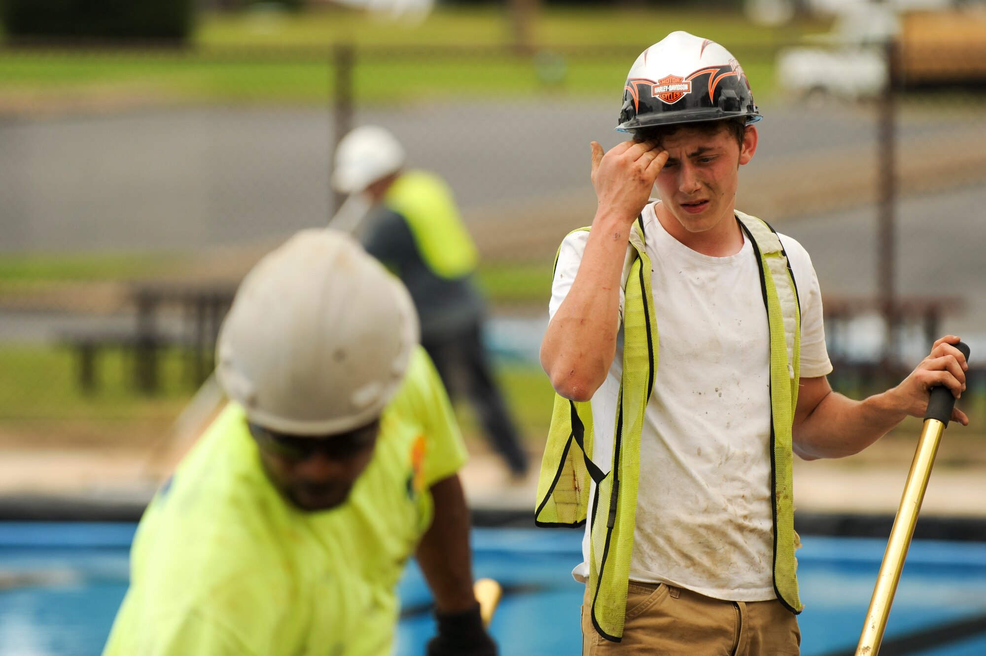 A contractor wipes the sweat from his face while working to complete the renovations at the base pool May 19, 2015, at Little Rock Air Force Base, Ark. New lockers were installed to keep belongings safe and dry while members enjoy the pool or soak up the sun in a lounge chair. (U.S. Air Force photo by Senior Airman Scott Poe)