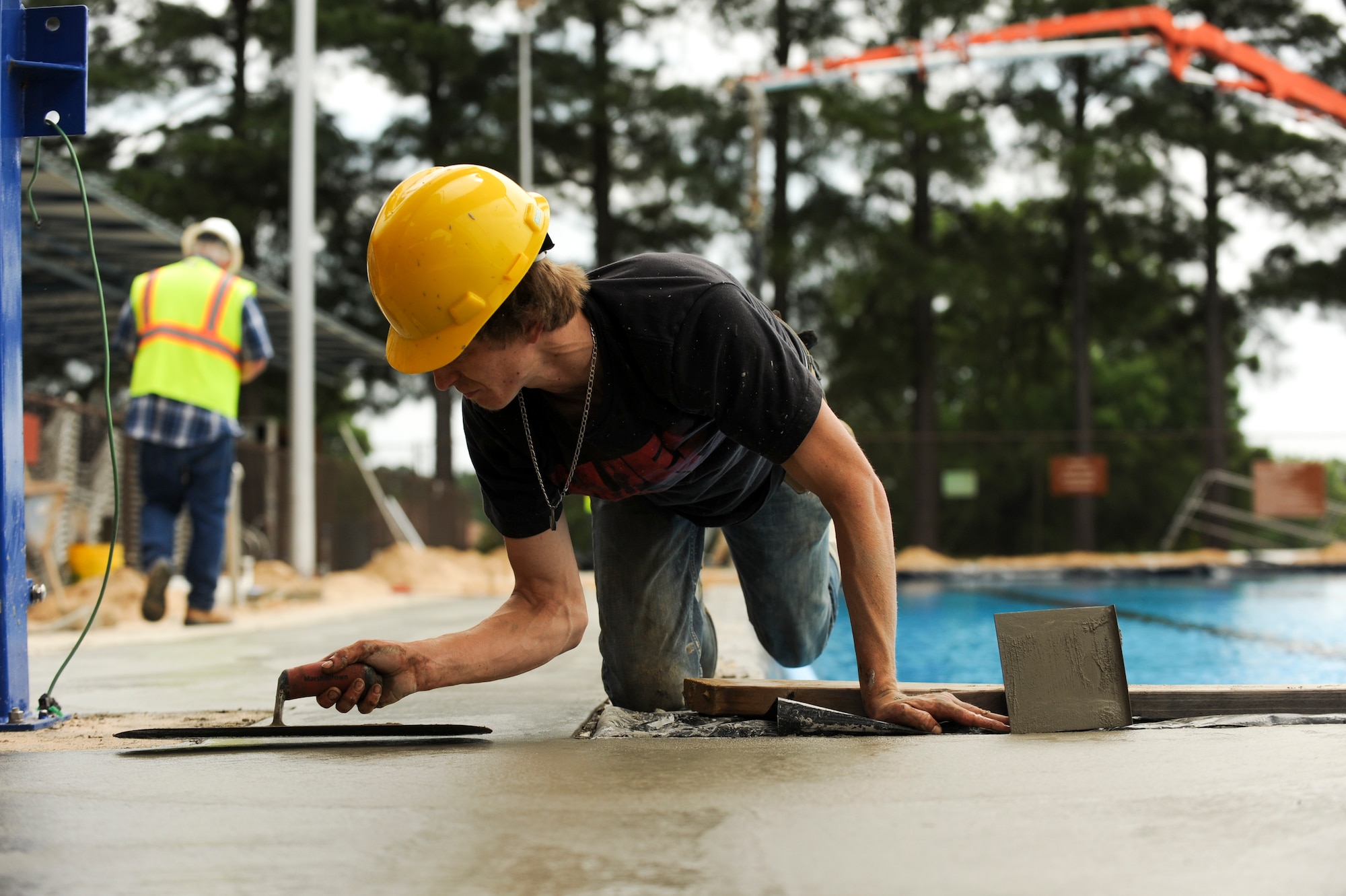 A contractor levels out freshly poured concrete while balancing on the edge of the base pool May 19, 2015, at Little Rock Air Force Base, Ark. A new liner, along with new pumps, was installed in both the kiddie pool and the main pool. (U.S. Air Force photo by Senior Airman Scott Poe) 