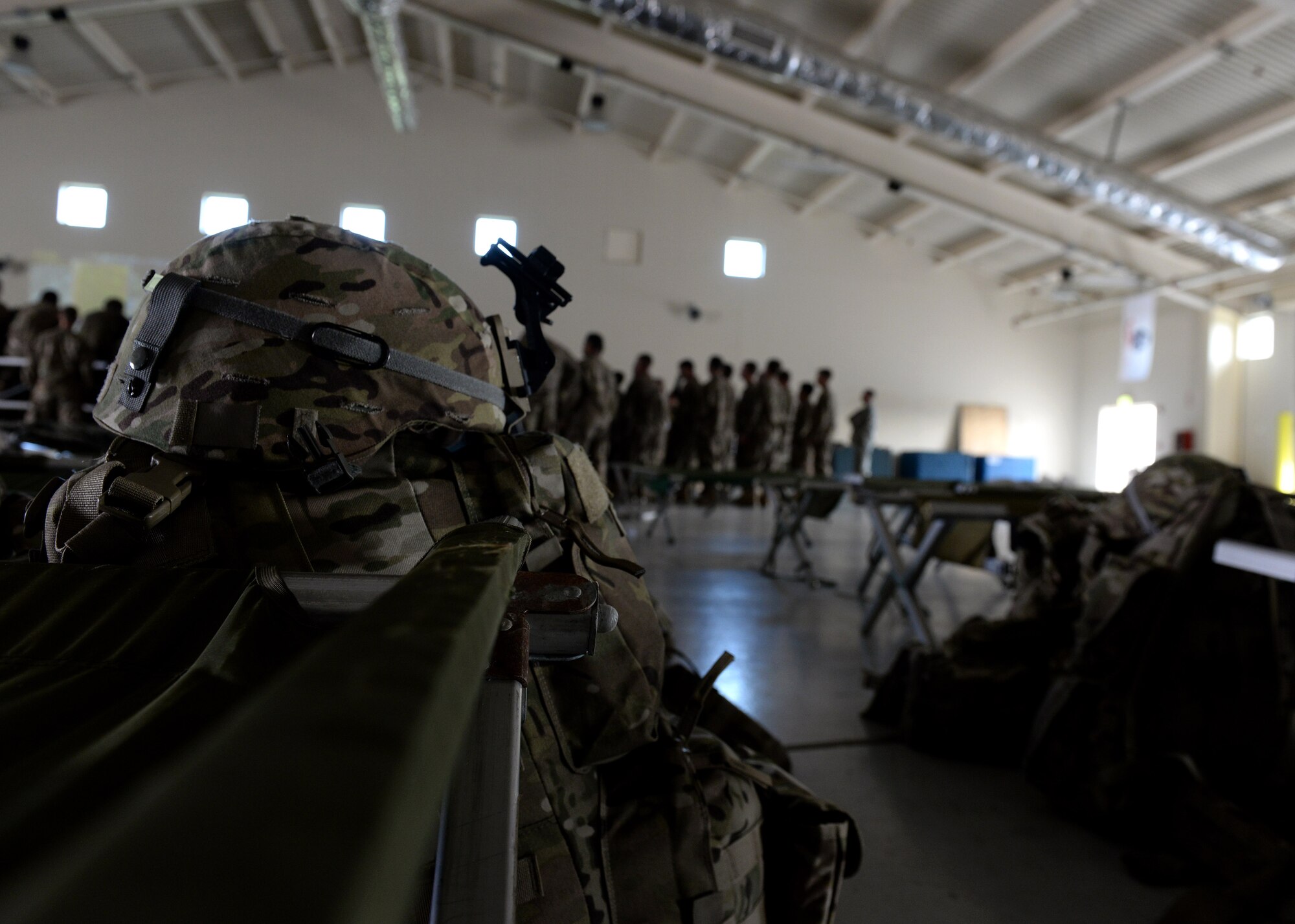 Jump gear sits by sleeping cots as U.S. Army paratroopers from the 173rd Airborne Brigade, Vicenza, gather for a pre-jump mission briefing at the Personnel Alert Holding Area, June 9, 2015, at Aviano Air Base, Italy. The U.S. Army and German Armed Forces deployed to Lithuania for a five-month joint training exercise. (U.S. Air Force photo by Airman 1st Class Cary Smith/Released)