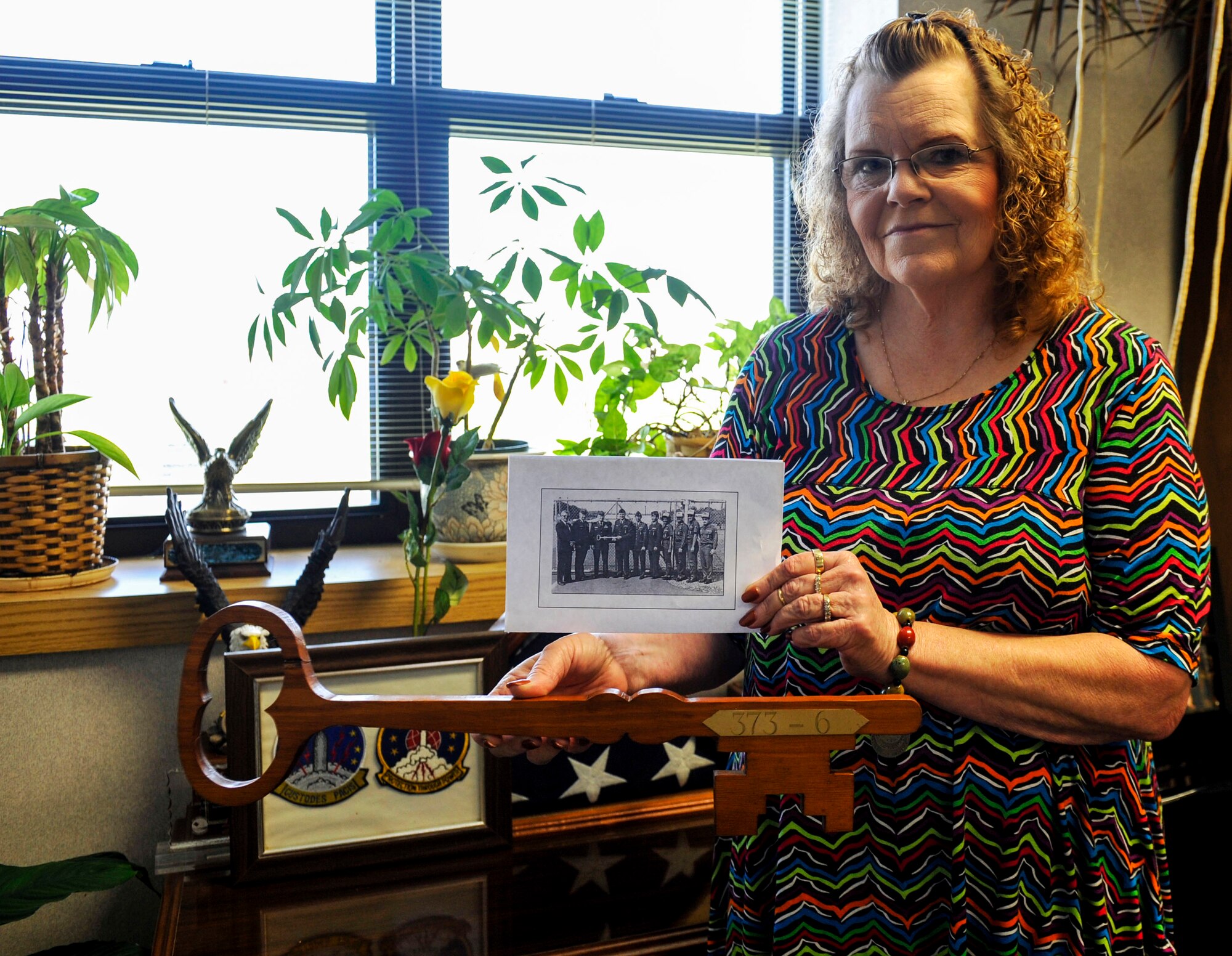 Jane Utley, a 19th Contracting Squadron procurement analyst, holds the ceremonial key and copy of a 1987 photo June 4, 2014 at Little Rock Air Force Base, Ark. The picture showed the presentation of the key to missile silo 373-6 during the deactivation ceremony of the Titan II missile silo in Antioch, Arkansas, when the Missileers turned over the site to the Civil Engineer Squadron for site decommissioning. (U.S. Air Force photo by Senior Airman Stephanie Serrano)