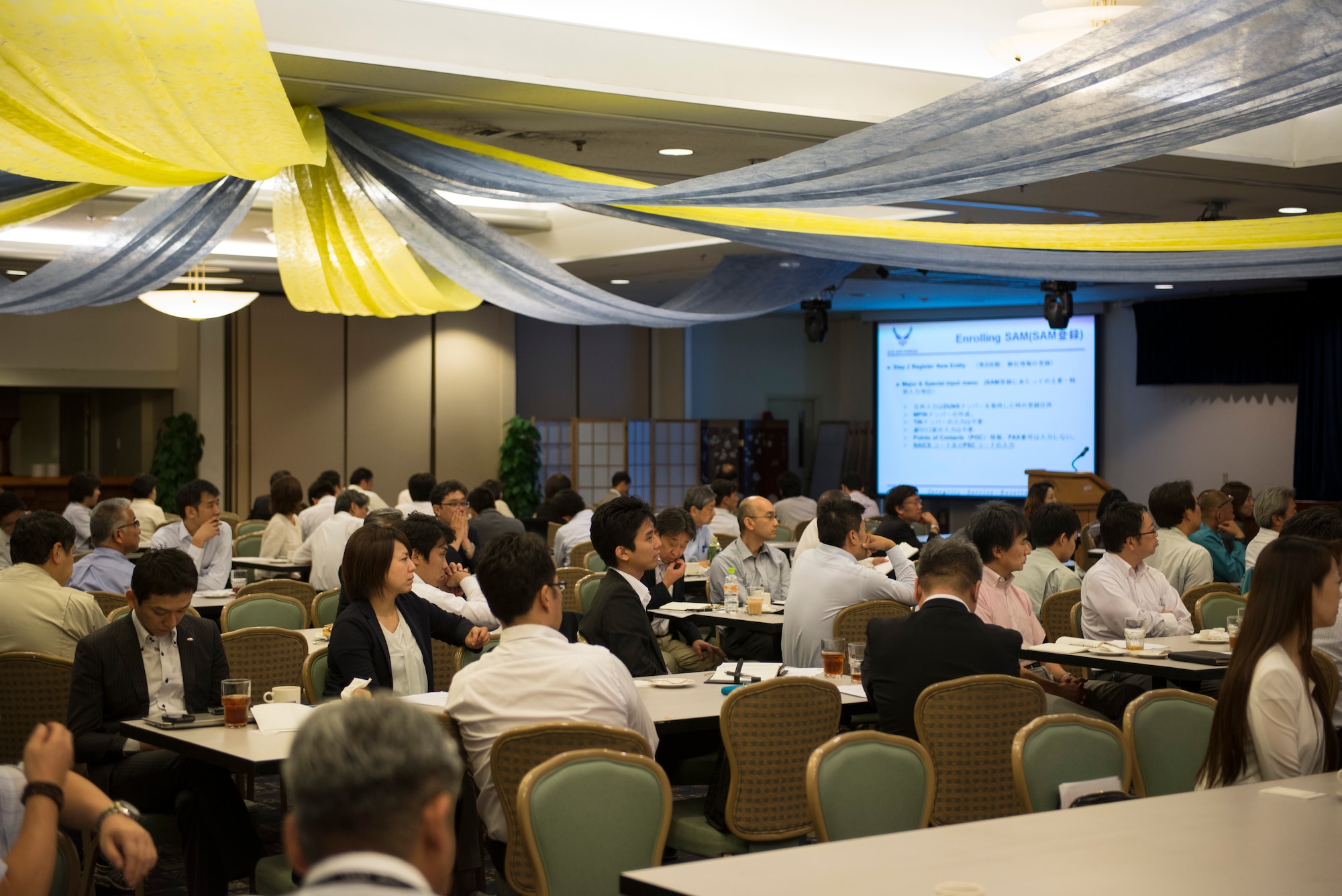 Local business representatives listen to a member of the 374th Contracting Squadron during a Vendor Fair at Yokota Air Base, Japan, June 10, 2015. The fair attracted more than 97 participants, representing 70 business, to learn about job opportunities at Yokota. (U.S. Air Force photo by Staff Sgt. Cody H. Ramirez/Released)