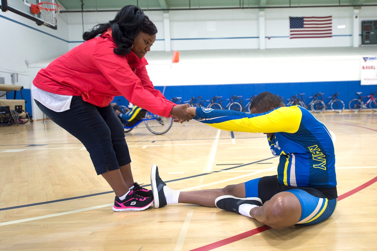 Ida Malone helps her husband, Navy Chief Petty Officer Averill Malone, stretch before cycling during the Navy’s training camp for the 2015 DoD Warrior Games at Ventura County Naval Station Port Hueneme in Oxnard, Calif., June 3, 2015. DoD photo by EJ Hersom