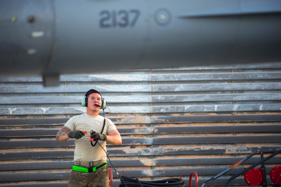 U.S. Air Force Staff Sgt. William Harris communicates with the pilot of an F-16 Fighting Falcon before a combat sortie on Bagram Airfield, Afghanistan, June 8, 2015. 
