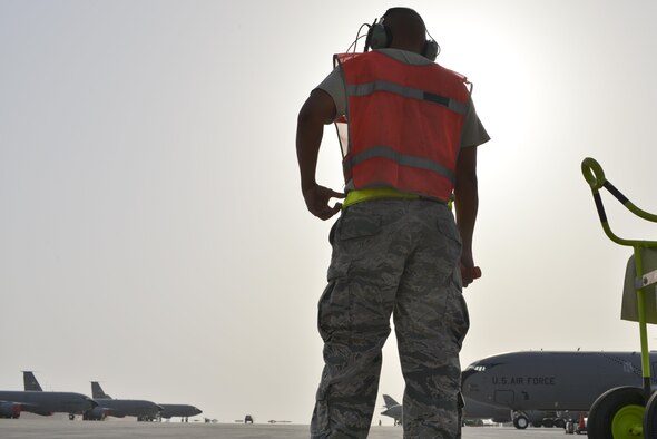 Technical Sgt. Anthony Atoigue, 340th Aircraft Maintenance Unit, waits for the KC-135 Stratotanker flown by the 379th Air Expeditionary Wing commander during his fini-flight to be directed for parking June 6, 2015 Al Udeid Air Base, Qatar. The 340th is composed of Airmen and aircraft from more than 70 different Active, Guard, and Reserve force providers supporting five different weapon systems. (U.S. Air Force photo/Staff Sgt. Alexandre Montes)