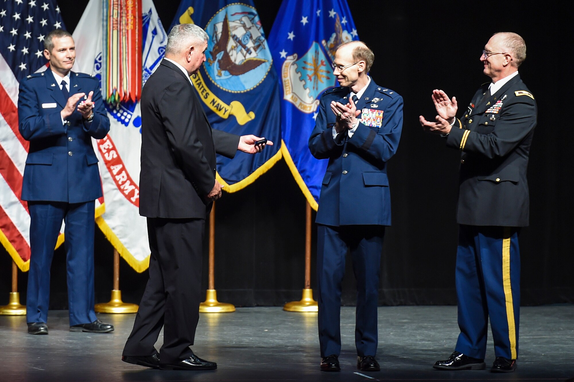 The 15th chief of staff of the Air Force Gen. Ronald Fogleman (left), is presented a momenta by Maj. Gen. Bart Iddins, 59th Medical Wing commander, and Col. Evan Renz, Brooke Army Medical Center commander during the San Antonio Uniformed Services Health Education Consortium (SAUSHEC) awards and graduation ceremony at the Lila Cockrell Theatre, San Antonio, Texas, June 5, 2015. SAUSHEC is responsible for all military graduate medical education in San Antonio. (U.S. Air Force photo by Staff Sgt. Michael Ellis) 