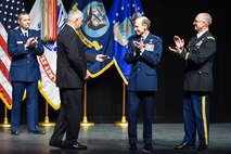 The 15th chief of staff of the Air Force Gen. Ronald Fogleman (left), is presented a momenta by Maj. Gen. Bart Iddins, 59th Medical Wing commander, and Col. Evan Renz, Brooke Army Medical Center commander during the San Antonio Uniformed Services Health Education Consortium (SAUSHEC) awards and graduation ceremony at the Lila Cockrell Theatre, San Antonio, Texas, June 5, 2015. SAUSHEC is responsible for all military graduate medical education in San Antonio. (U.S. Air Force photo by Staff Sgt. Michael Ellis) 