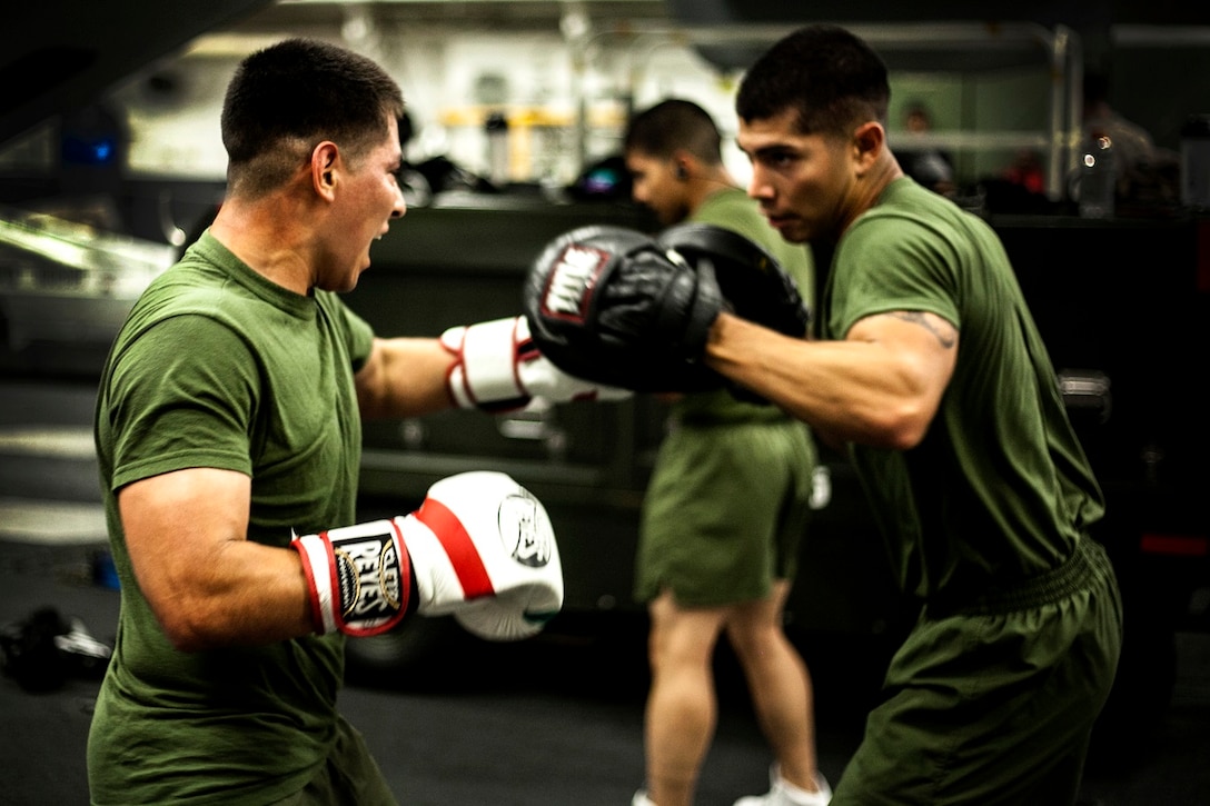 U.S. Marine Cpl. Roman Fernandez, right, instructs a Marine on punching techniques in the hangar bay of the USS Essex (LHD 2) in the Philippine Sea, June 2, 2015. Fernandez is a team leader with Lima Company, Battalion Landing Team 3rd Battalion, 1st Marine Regiment, 15th Marine Expeditionary Unit. The Marines are learning boxing techniques to improve their mental and physical well-being during their seven-month deployment. (U.S. Marine Corps photo by Cpl. Elize McKelvey/Released)