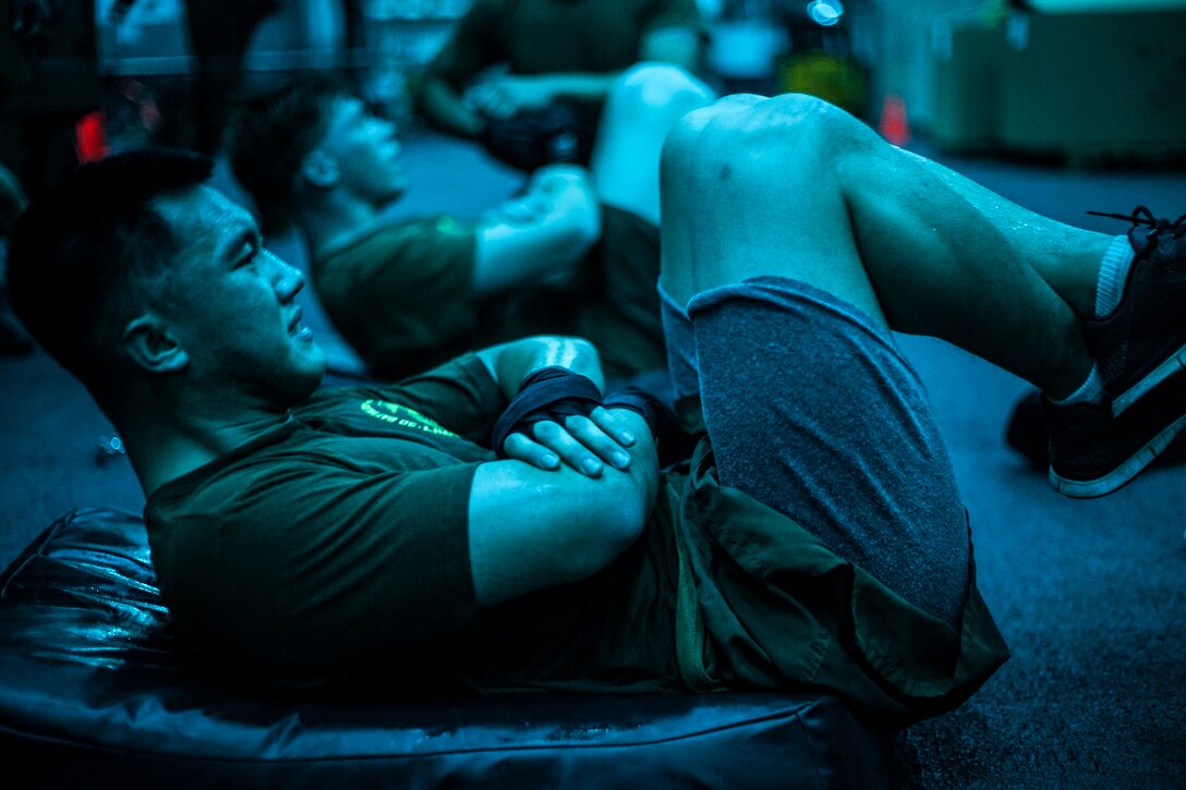 U.S. Marines pump out crunches in the hangar bay of the USS Essex (LHD 2) in the Philippine Sea, June 2, 2015. The Marines with Battalion Landing Team 3rd Battalion, 1st Marine Regiment, 15th Marine Expeditionary Unit are learning boxing techniques to improve their mental and physical well-being during their seven-month deployment. (U.S. Marine Corps photo by Cpl. Elize McKelvey/Released)