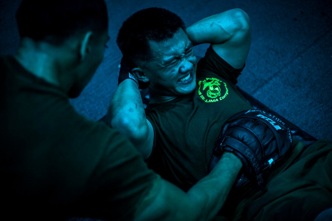 U.S. Marine Cpl. Kuamutsua Xiong, right, concentrates on his breathing during a body hardening session in the hangar bay of the USS Essex (LHD 2) in the Philippine Sea, June 2, 2015. Xiong is a company radio operator with Lima Company, Battalion Landing Team 3rd Battalion, 1st Marine Regiment, 15th Marine Expeditionary Unit. The Marines are learning boxing techniques to improve their mental and physical well-being during their seven-month deployment. (U.S. Marine Corps photo by Cpl. Elize McKelvey/Released)
