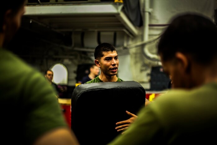 U.S. Marine Cpl. Roman Fernandez gives a boxing lesson in the hangar bay of the USS Essex (LHD 2) in the Philippine Sea, June 2, 2015. Fernandez is a team leader with with Lima Company, Battalion Landing Team 3rd Battalion, 1st Marine Regiment, 15th Marine Expeditionary Unit. The Marines are learning boxing techniques to improve their mental and physical well-being during their seven-month deployment. (U.S. Marine Corps photo by Cpl. Elize McKelvey/Released)