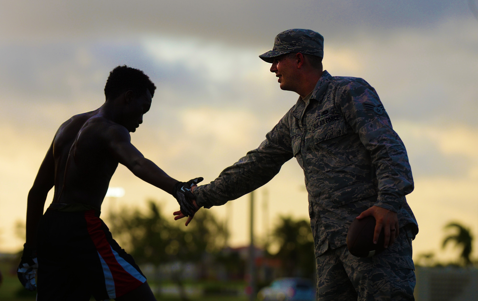 Senior Airman Presley Griffith, a 36th Mobility Response Squadron executive assistant, right, compliments a high school athlete on a practice drill June 6, 2015, at Andersen Air Force Base, Guam. Griffith is a volunteer football coach and offers a free football spring practice camp three times per week as volunteer coach as a preseason training opportunity to Andersen AFB student athletes. (U.S. Air Force photo/Senior Airman Alexander W. Riedel)