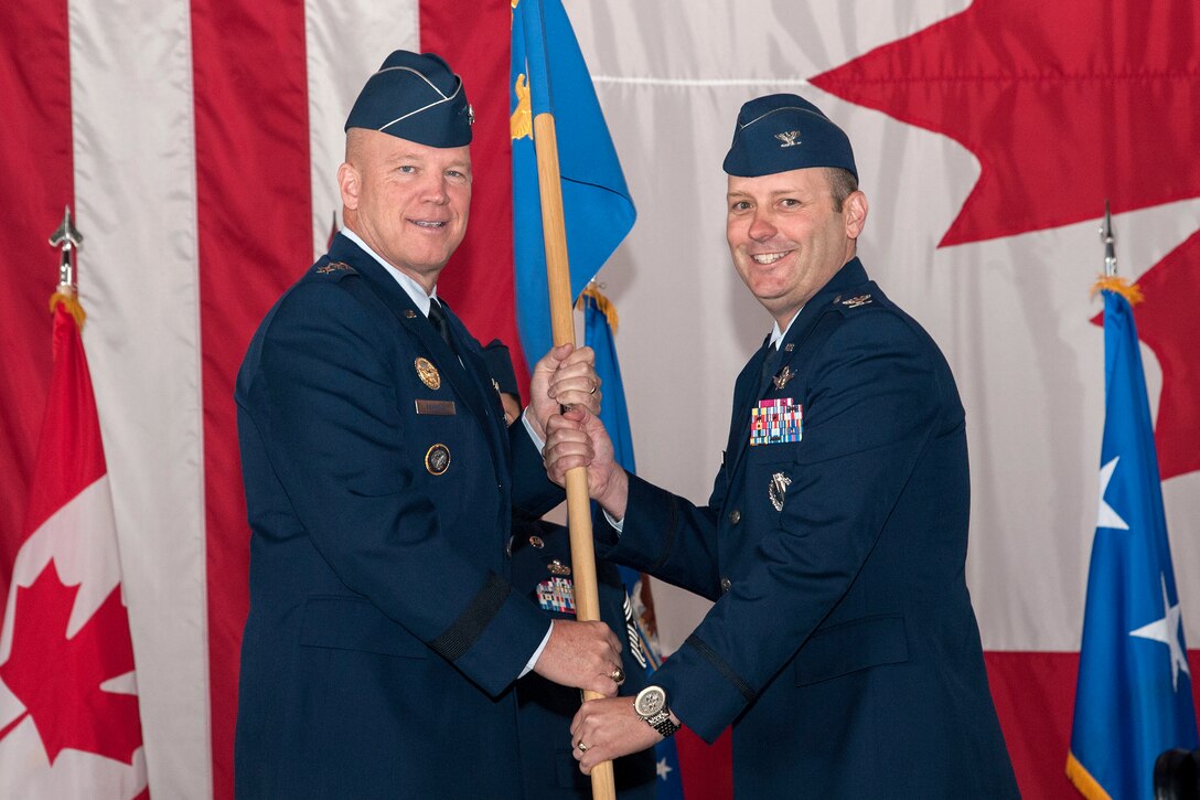 PETERSON AIR FORCE BASE, Colorado -- Lt. Gen. John W. "Jay" Raymond, commander, 14th Air Force (Air Forces Strategic) and Joint Functional Component Command for Space, passes the 21st Space Wing guidon to Col. Douglas A. Schiess, incoming 21st SW commander, during the wing change of command ceremony June 12 in hangar 140. Before taking command of the wing, Schiess was Director of Space Forces, U.S. Air Forces Central Command, U.S. Central Command. (U.S. Air Force photo by Craig Denton)