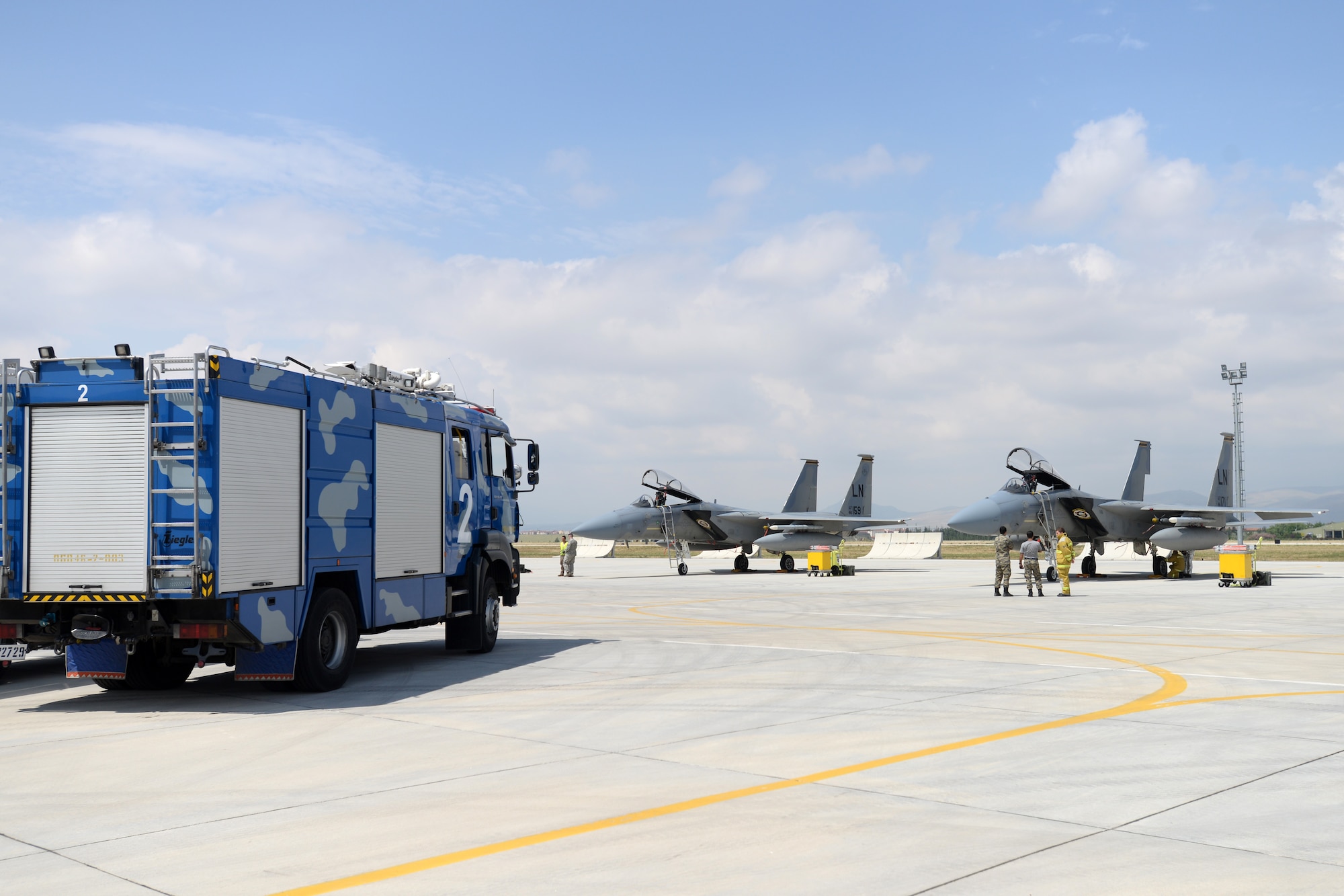 A fire truck sits parked on the flightline at 3rd Main Jet Base, Konya, Turkey, across from two F-15C Eagles from the 493rd Fighter Squadron, 48th Fighter Wing, Royal Air Force Lakenheath, England, June 11, 2015. Tech. Sgt. Jeremy Hill, 48th Civil Engineer Squadron station chief, one of about 250 personnel from the 48th Fighter Wing, Royal Air Force Lakenheath, England, participating in Anatolian Eagle 15, was facilitating a proficiency exercise with four Turkish Air Force firefighters. (U.S. Air Force photo by Tech. Sgt. Eric Burks/Released)