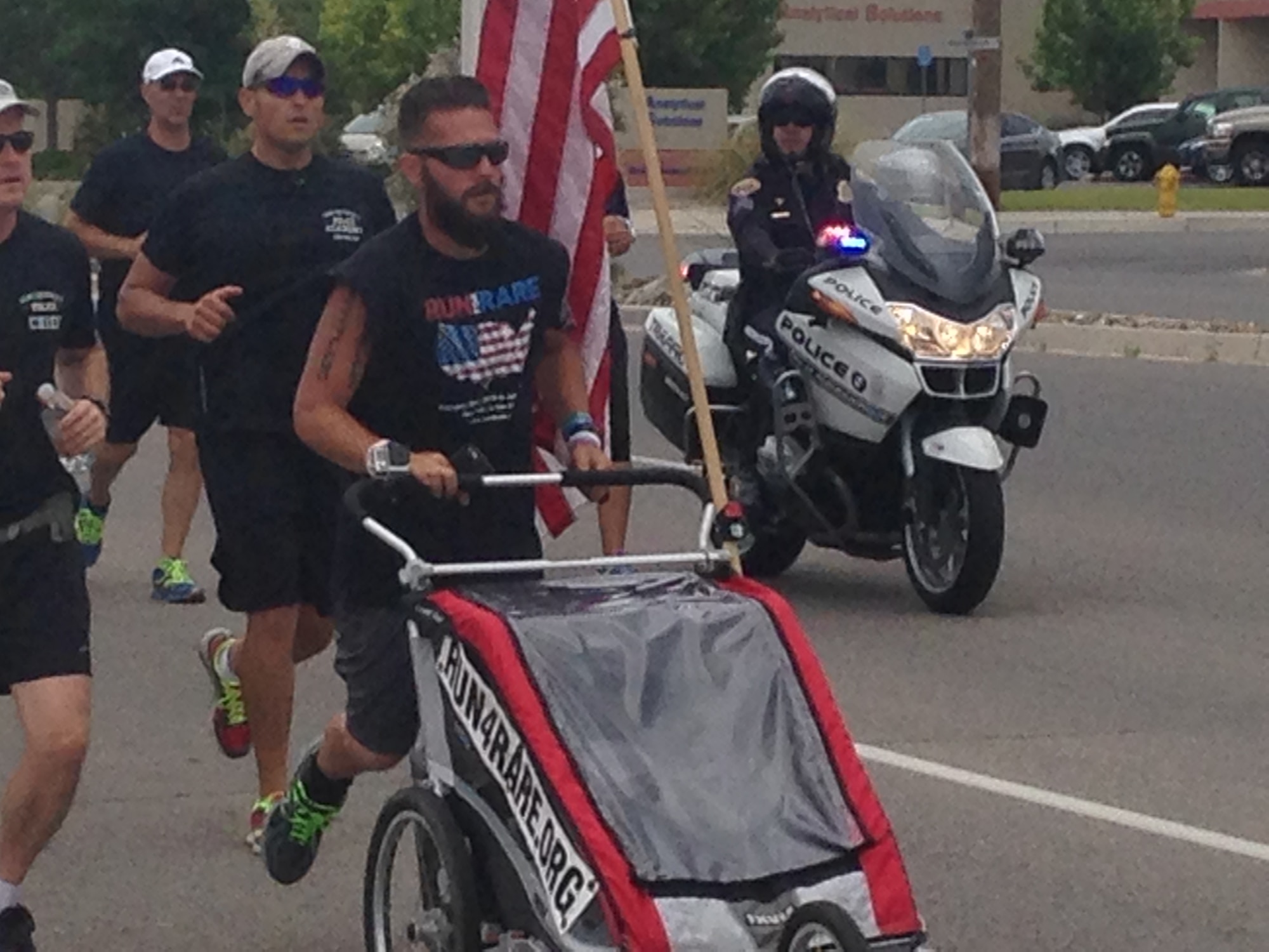 Noah Coughlan runs onto Kirtland with a police escort June 5. Coughlan stopped at the base while on a 3,100-mile trek across the country to raise awareness for rare diseases.  (Photo by Kendahl Johnson)