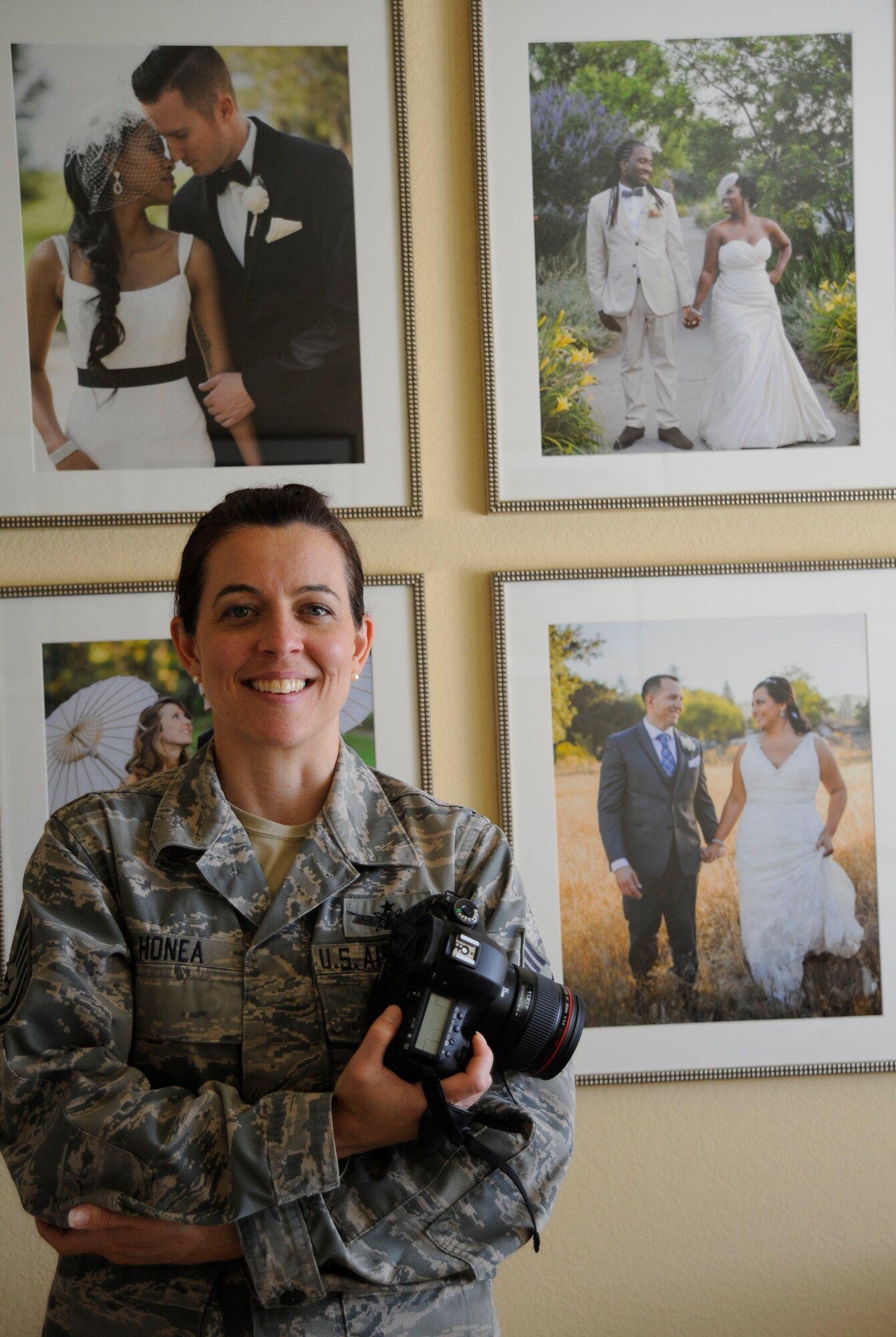 Tech. Sgt. Danielle Honea, 30th Operations Support Squadron flight chief of weapons and tactics, stands in front of samples of her photography, June 11, 2015, Vandenberg Air Force Base, Calif. As a business owner and wedding photographer, Honea starts her creative process by conversing with prospective clients in her small home office. (U.S. Air Force photo by Airman 1st Class Ian Dudley/Released)