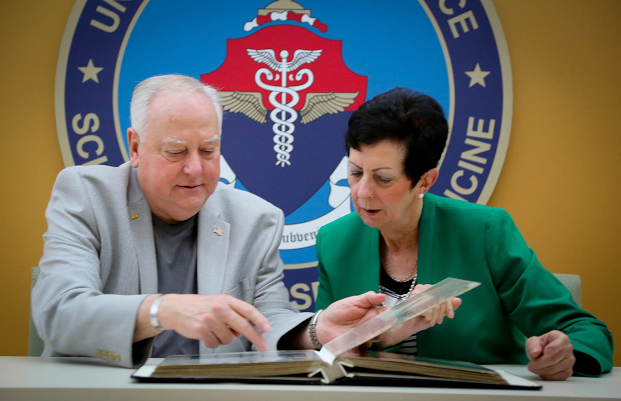 Ray Snedegar and Regina Aune look through a scrapbook of photos and articles collected by Snedegar on Operation Babylift prior to Aune's presentation at the U.S. Air Force School of Aerospace Medicine June 4. (Photo courtesy of Cox Media Group Ohio)