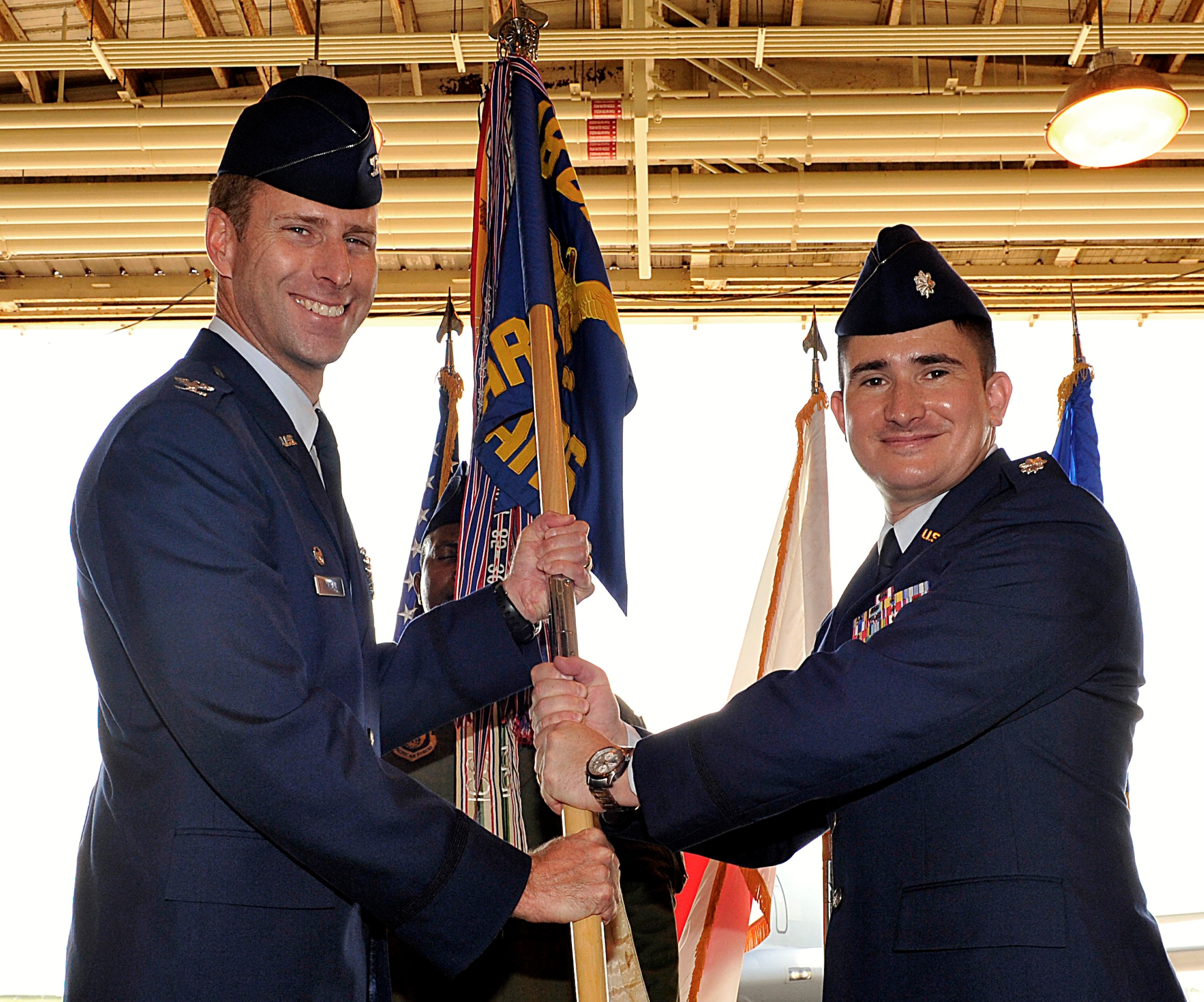 U.S. Air Force Col. David Mineau, 18th Operations Group commander, passes the 909th Air Refueling Squadron guidon to Lt. Col. Jonathan Burdick, 909th ARS commander, during a change of command ceremony at Kadena Air Base, Japan, June 12, 2015. The change of command is a traditional military ceremony in which the departing commander assembles his troops for presentation to the incoming commander. (U.S. Air Force photo by Naoto Anazawa)
