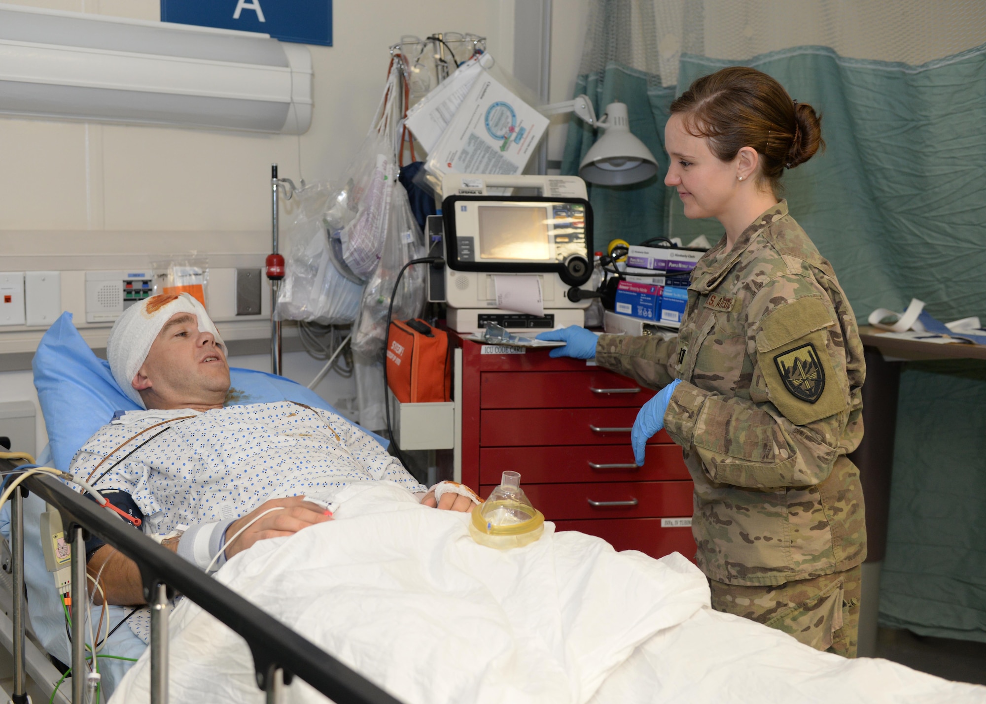U.S. Air Force Capt. Mavis Bean, 455th Expeditionary Medical Operations Squadron clinical care nurse, talks with a volunteer training patient June 11, 2015, at Bagram Airfield, Afghanistan. Bean works in the intensive care unit at Afghanistan’s most advanced medical facility, the Craig Joint Theater Hospital, and is responsible for treating trauma patients. (U.S. Air Force photo by Senior Airmen Cierra Presentado/Released)