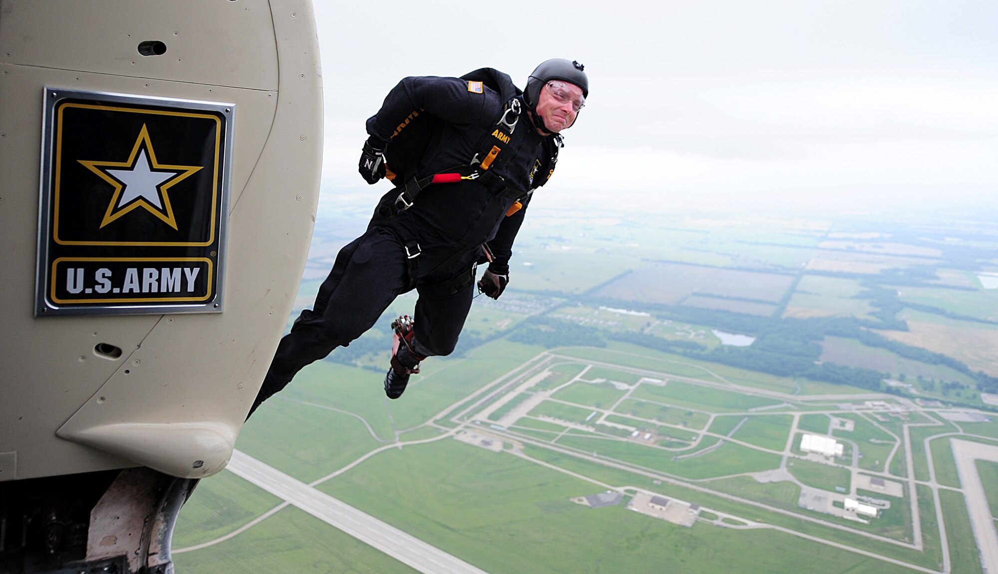 A member of the U.S. Army Golden Knights Parachute Team launches out of the aircraft June 13, 2015, during the Wings Over Whiteman air show at Whiteman Air Force Base, Mo. Flares emitting red smoke were attached to the Golden Knights’ boots to ignite once they jumped out. (U.S. Air Force photo by Airman 1st Class Jazmin Smith/Released)