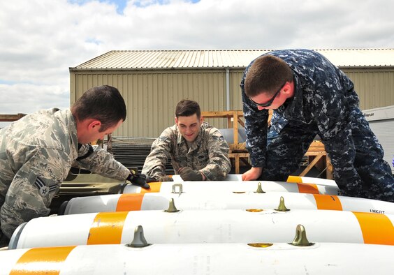 A U.S. Navy mineman, from Navy Munitions Command Unit Charleston, and U.S. Air Force technicians, from the 5th Munitions Squadron, rotate an inert MK-62 Quick Strike Mine to secure a MK-15 tail fin during a mine build at Royal Air Force Fairford, England, June 10, 2015. The mines were built for a BALTOPS 15 exercise where B-52H Stratofortresses tested their ability to precisely drop munitions into a target zone off the coast of Sweden. BALTOPS provides an opportunity for personnel from different services and nations to engage in realistic maritime training to build experience and teamwork and strengthen interoperability. (U.S. Air Force photo/Senior Airman Malia Jenkins)  